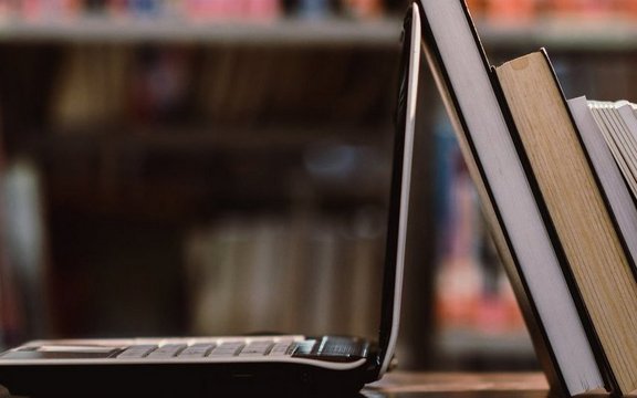 Ein Laptop und mehrere Bücher sind zu sehen