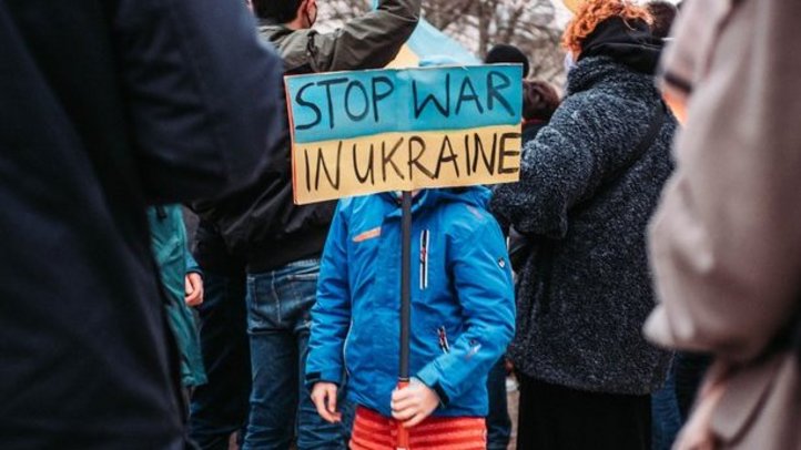 Ein Kind in einer Menschenmenge mit einem Schild "Stop war in Ukraine"