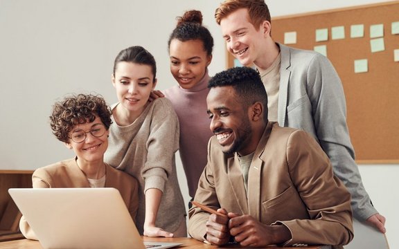 Mehrere Menschen schauen auf einen Laptop