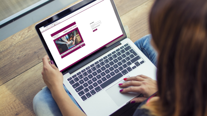 Eine Frau sitzt vor dem Laptop und besucht eine Website.