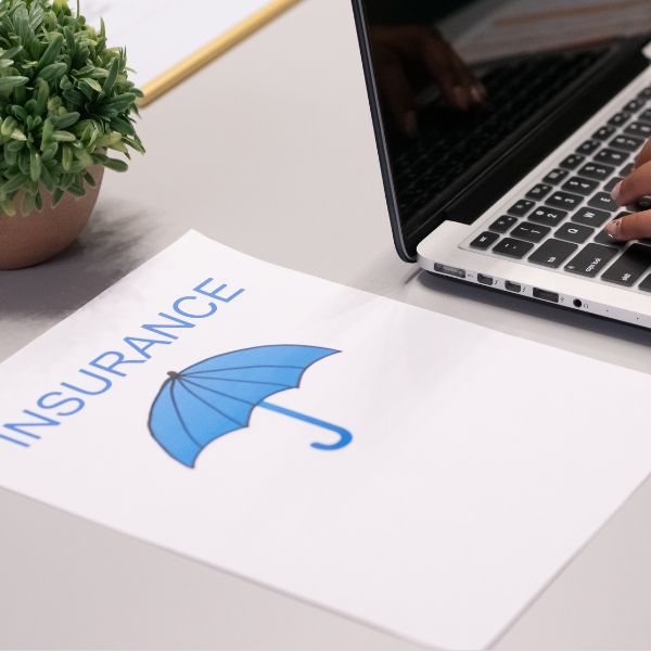 Laptop, daneben liegt ein Blatt mit dem Text "Insurance"